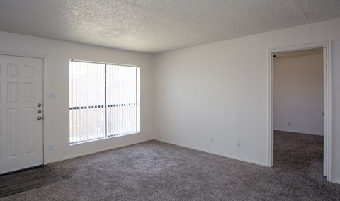 an empty living room with a window and a door