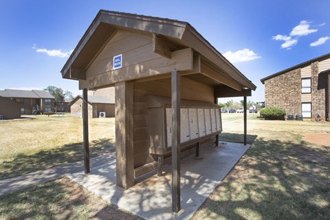 a small wooden kiosk with a bench in a park