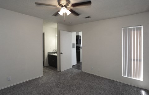 an empty living room with a ceiling fan and a kitchen