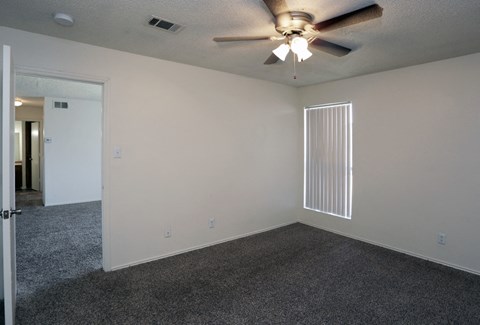 the living room of an empty home with a ceiling fan