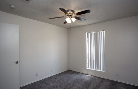 an empty room with a ceiling fan and a window