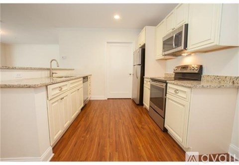 A kitchen with white cabinets and a wooden floor.