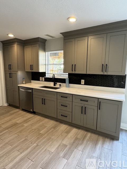 A kitchen with wooden floors and grey cabinets.