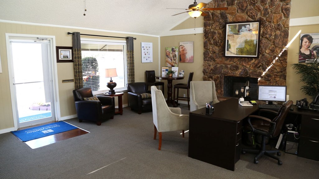 a living room with a desk and chairs and a fireplace