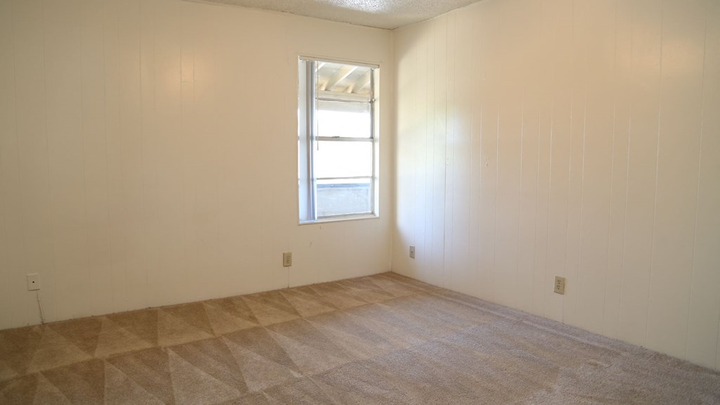 an empty room with a window and a tiled floor