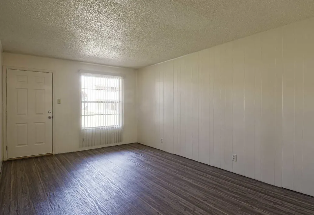 an empty living room with wood floors and a white door