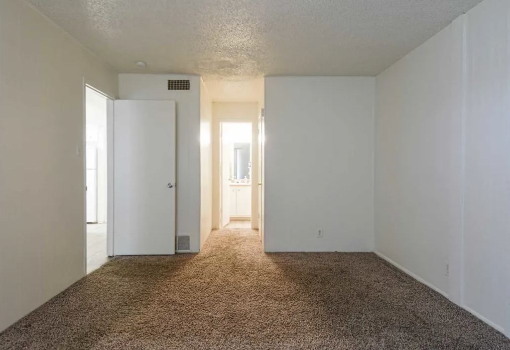 an empty living room with white walls and carpet