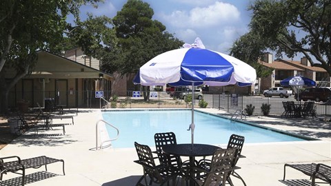 a swimming pool with a table and chairs under an umbrella