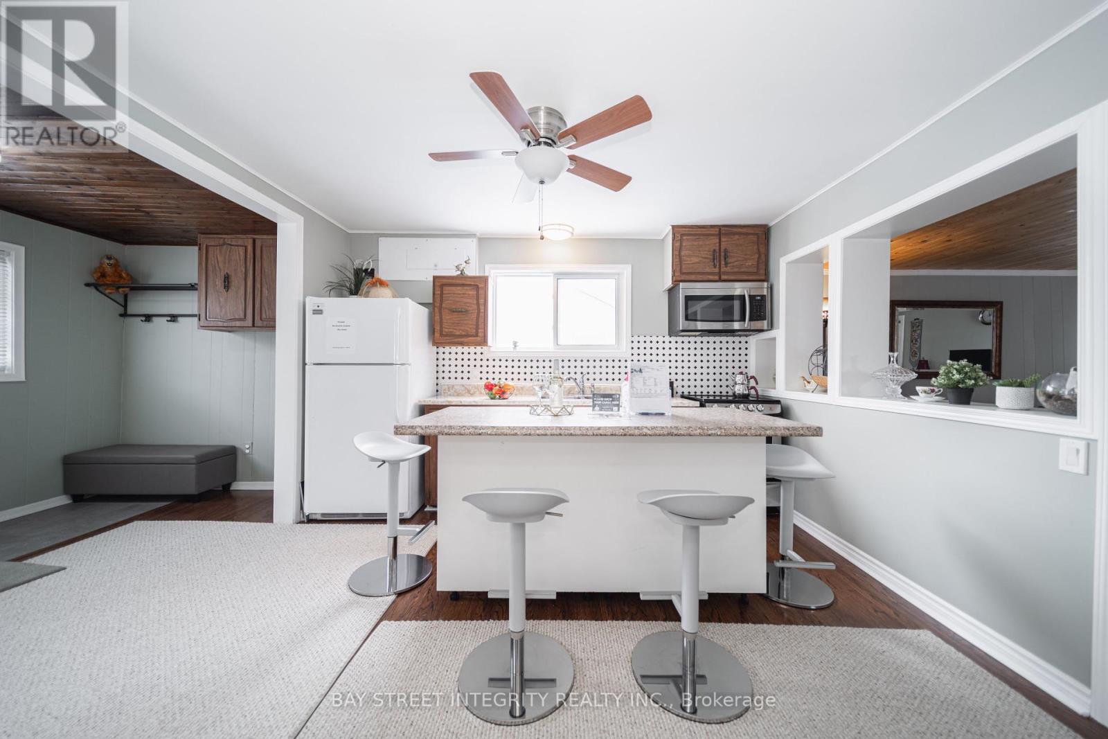 A kitchen with white appliances and a white island with two stools.