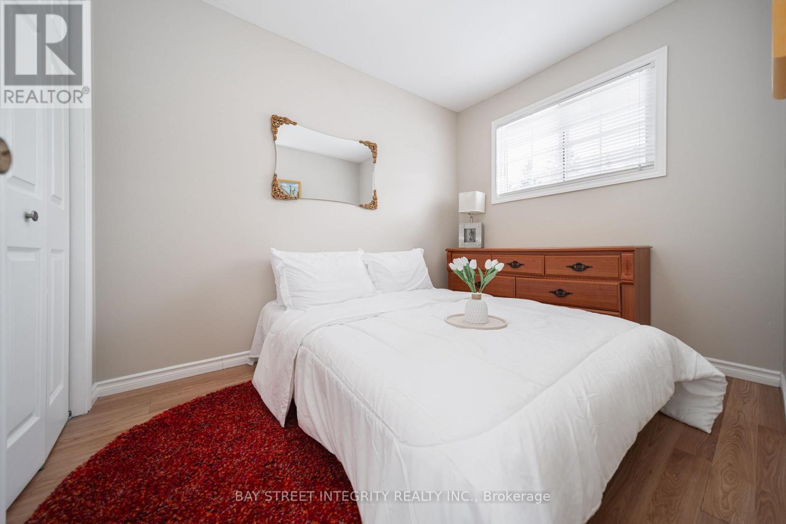 A bedroom with a white bed and a red rug.