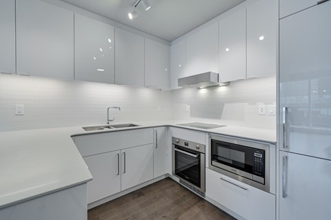 A modern kitchen with white cabinets and appliances.