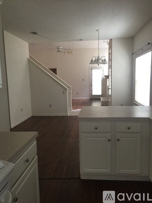 A kitchen with white cabinets and a wooden floor.