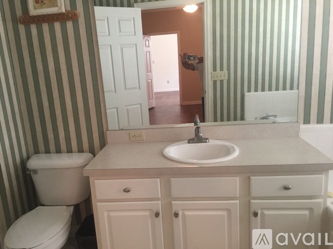 A bathroom with striped walls and a white toilet.