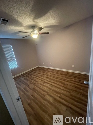 A room with a ceiling fan and wooden flooring.