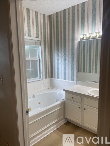 A bathroom with striped wallpaper and a white bathtub.