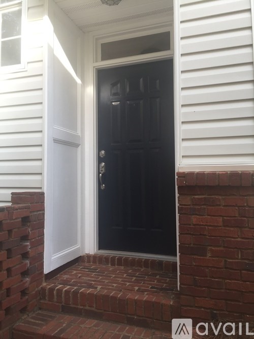 A black door is open to a white house.