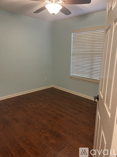 A room with wooden flooring and a ceiling fan.