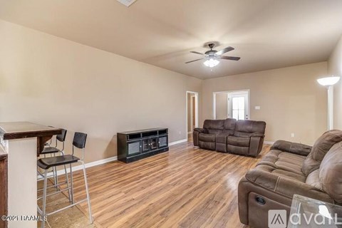 A living room with a brown leather couch and a television.