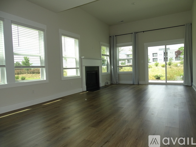 A spacious room with wooden floors and large windows.