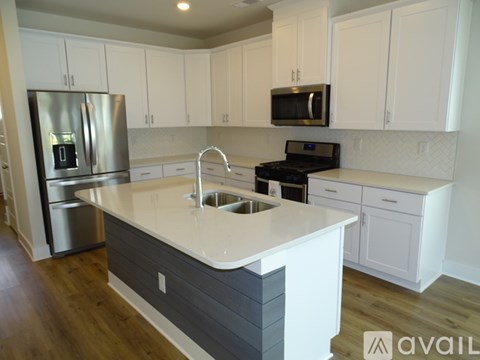 A kitchen with white cabinets and a grey island.