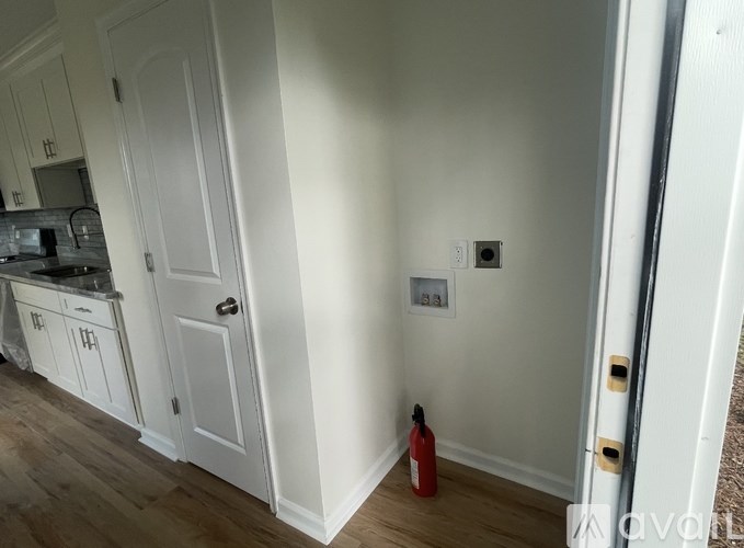 A kitchen with white cabinets and a red fire extinguisher on the floor.