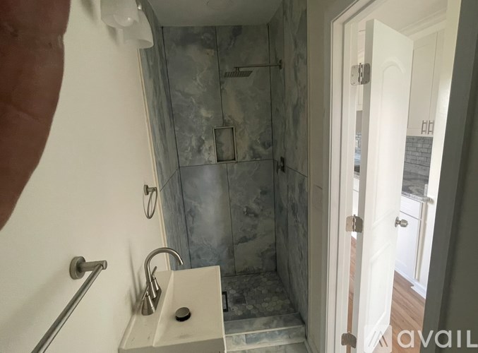 A bathroom with a marble shower and a white sink.