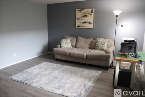 A living room with a couch, a rug, a lamp, and a painting on the wall.