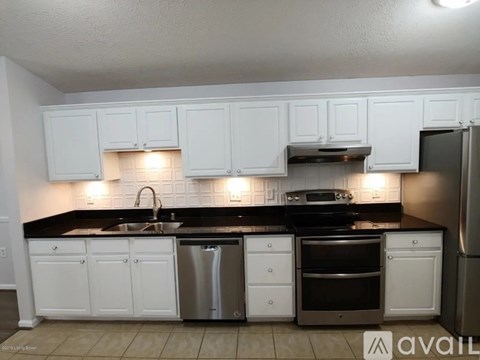 A kitchen with white cabinets and black countertops.