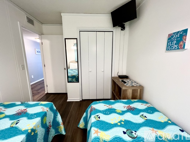 A bedroom with two beds and a TV mounted on the wall.
