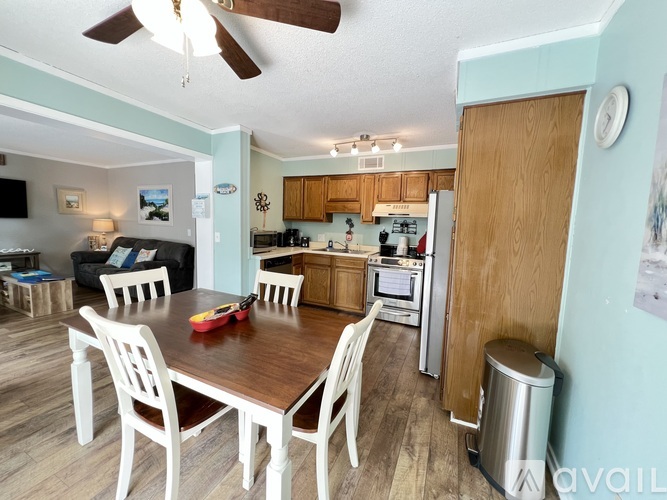 A kitchen with a table and chairs in the foreground and a refrigerator in the background.