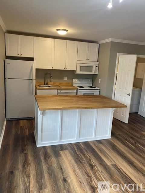 A kitchen with white cabinets and a wooden island.