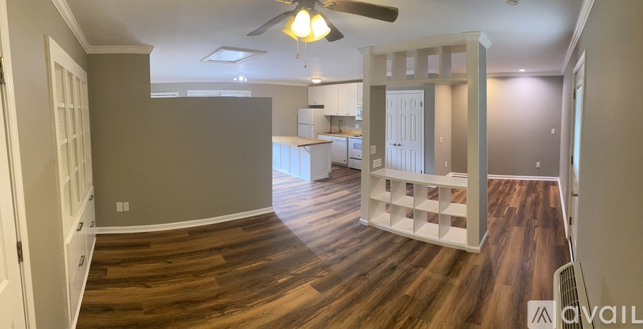 A spacious room with wooden floors and a ceiling fan.