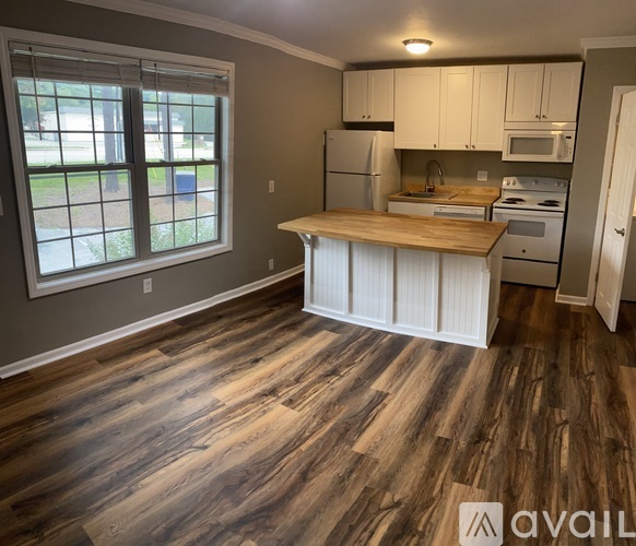 A kitchen with wooden floors and white cabinets.