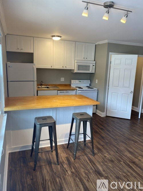 A kitchen with white cabinets and a wooden island.