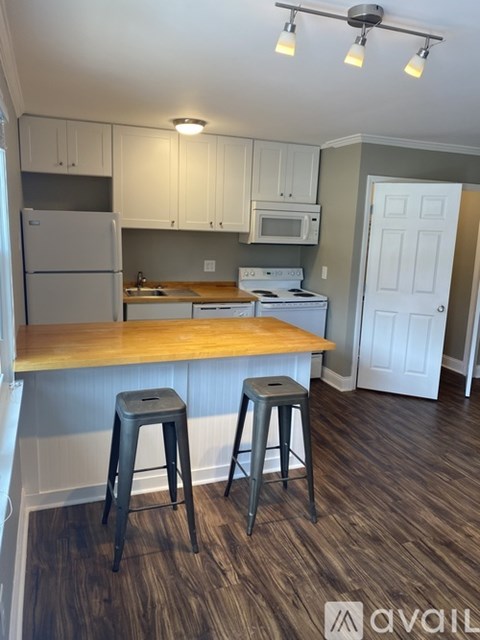 A kitchen with white cabinets and a wooden island.