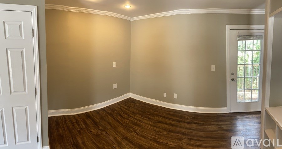 A room with a white door and a wooden floor.
