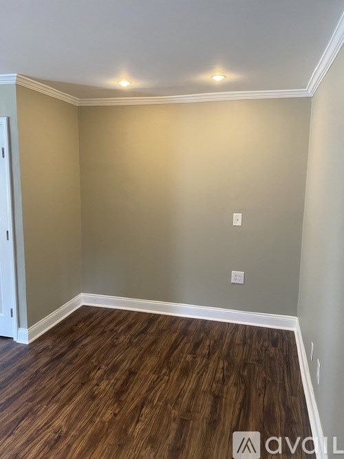 A room with wooden flooring and a white baseboard.