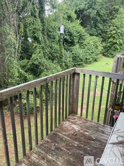 A deck with a view of a grassy area and trees.