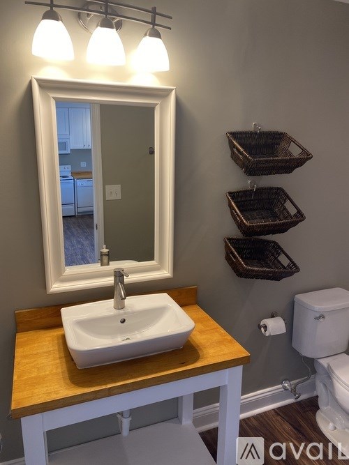 A bathroom with a sink, mirror, and baskets.