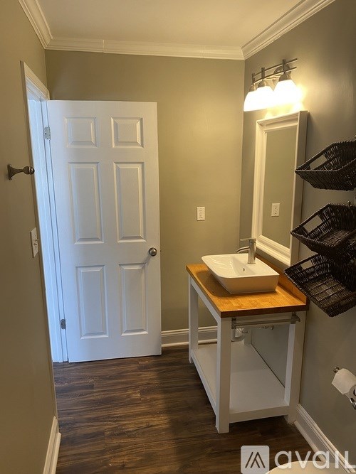 A bathroom with a white door and a wooden vanity.