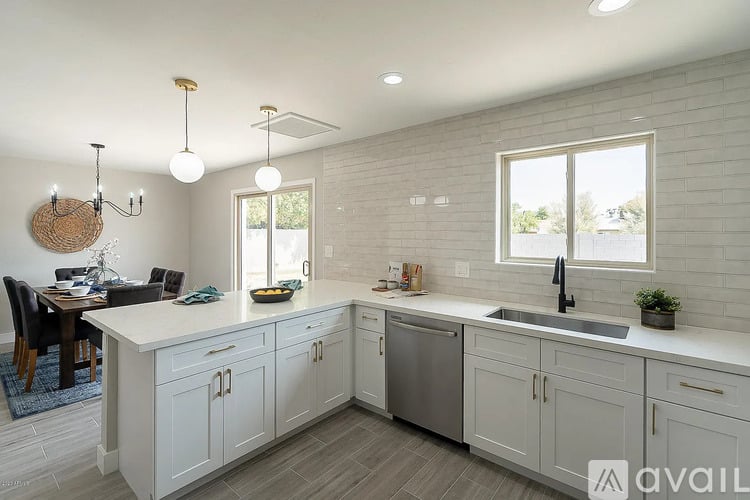 A kitchen with white cabinets and a large island with a bowl of fruit on it.