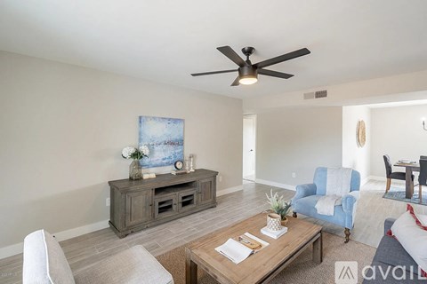 A living room with a ceiling fan and a painting on the wall.