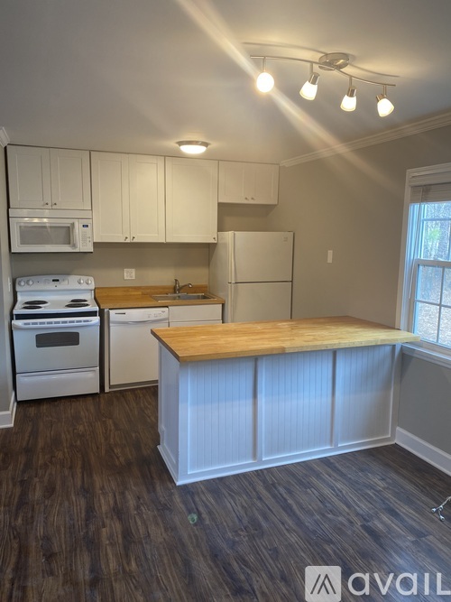 A kitchen with white appliances and wooden countertops.