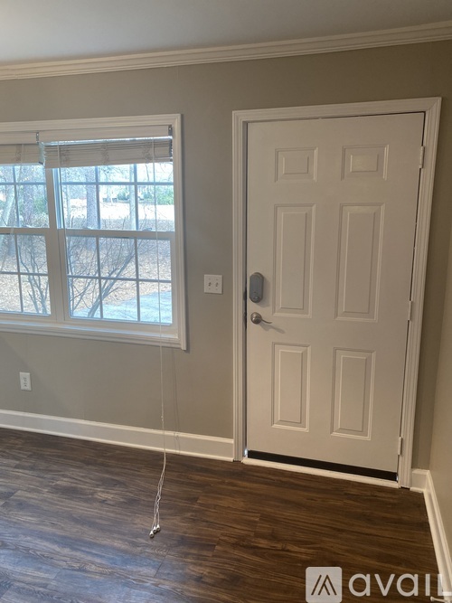A white door is on the right side of a window with blinds.
