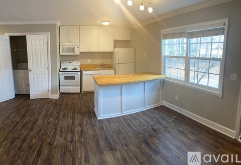 A kitchen with white cabinets and a wooden island.