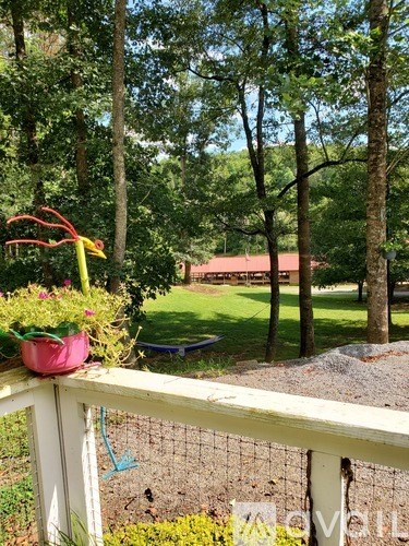 A white fence with a red ribbon and a pink pot with flowers on it.