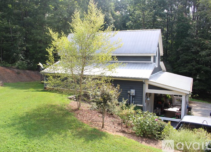 A house with a grey roof and a tree in front of it.