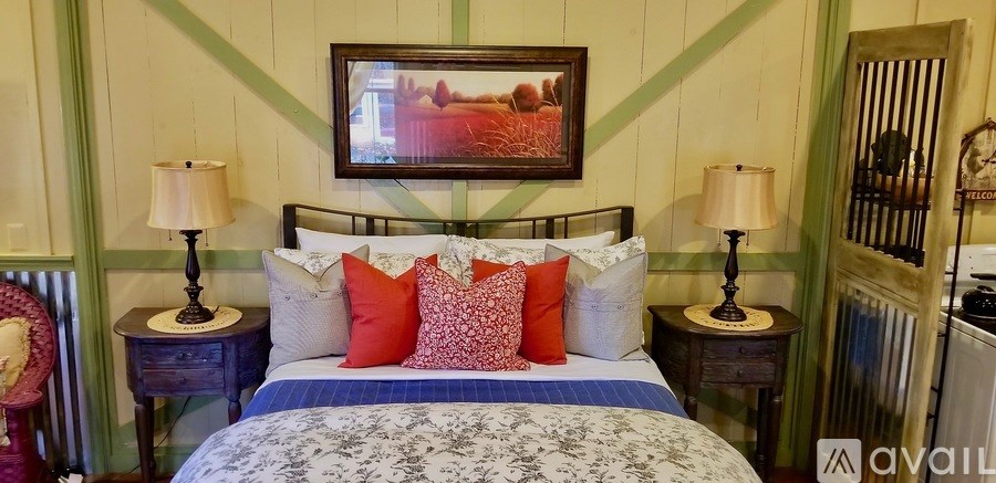 A bedroom with a bed, two lamps, and a painting on the wall.