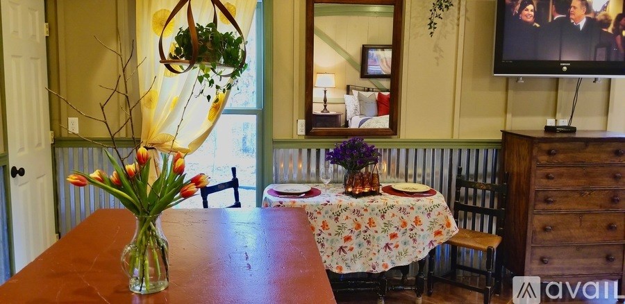 A dining room with a table set for two and a vase of flowers on the table.