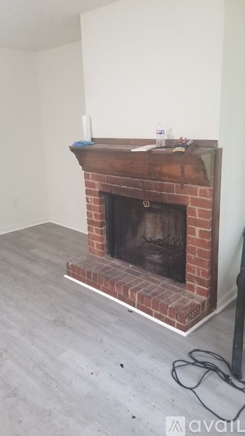 A brick fireplace with a white mantle and a white wall behind it.